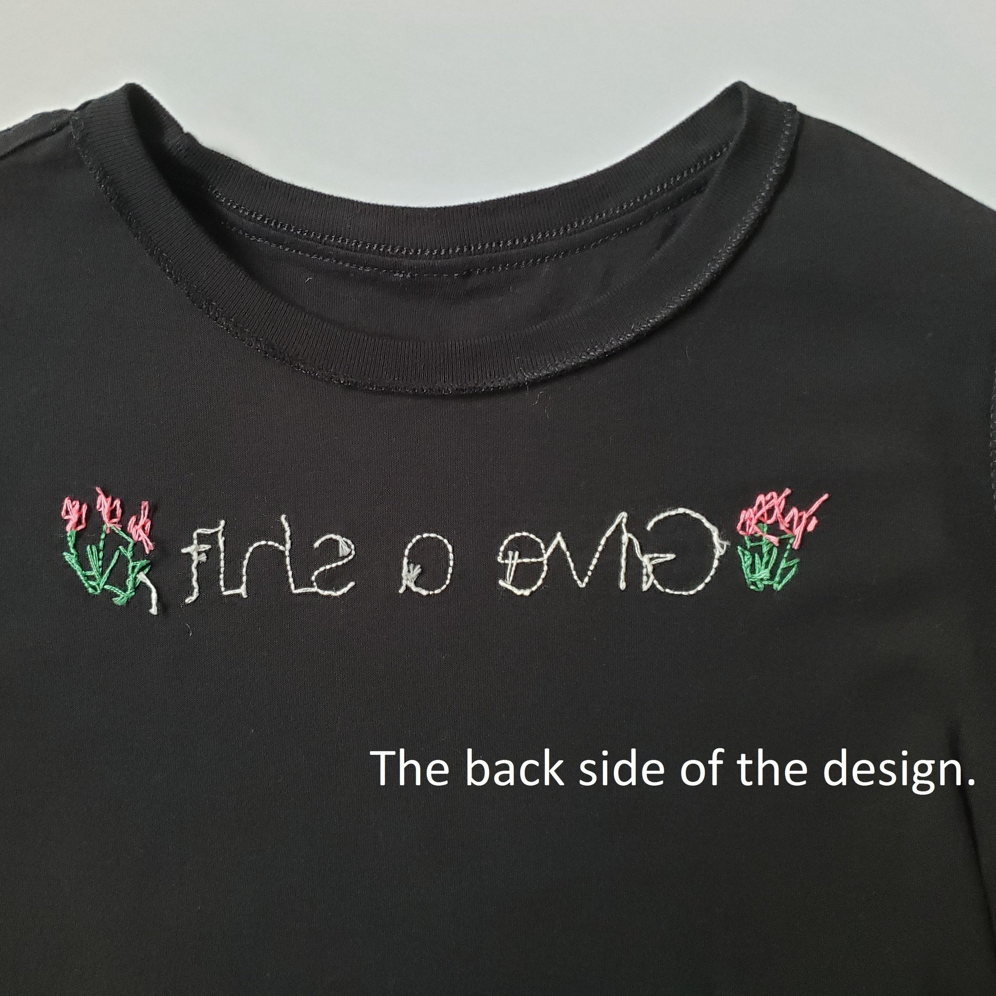 The back side of the design, included so folks can see how tidy the stitching is. You can see the lines are clean and there are no bundles of thread, just clean lines and "give a shit"  with two tulips. 